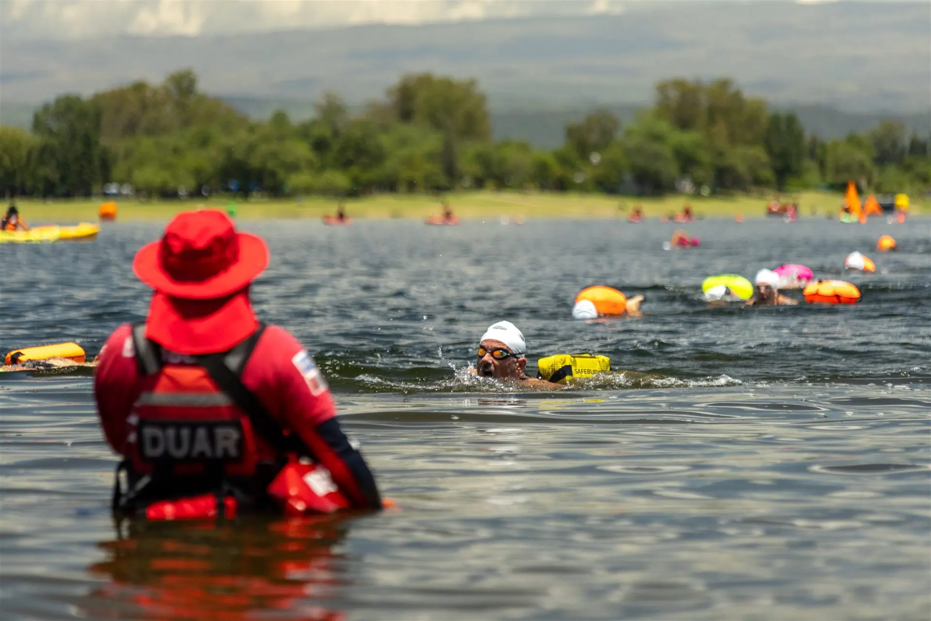 Nadadores atravesando el lago acompañados por el operativo de seguridad